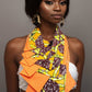 Woman wearing a colorful patterned top with an orange necktie  against a gray background