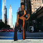 Woman posing on a city street wearing a two piece pants set with tall buildings in the background