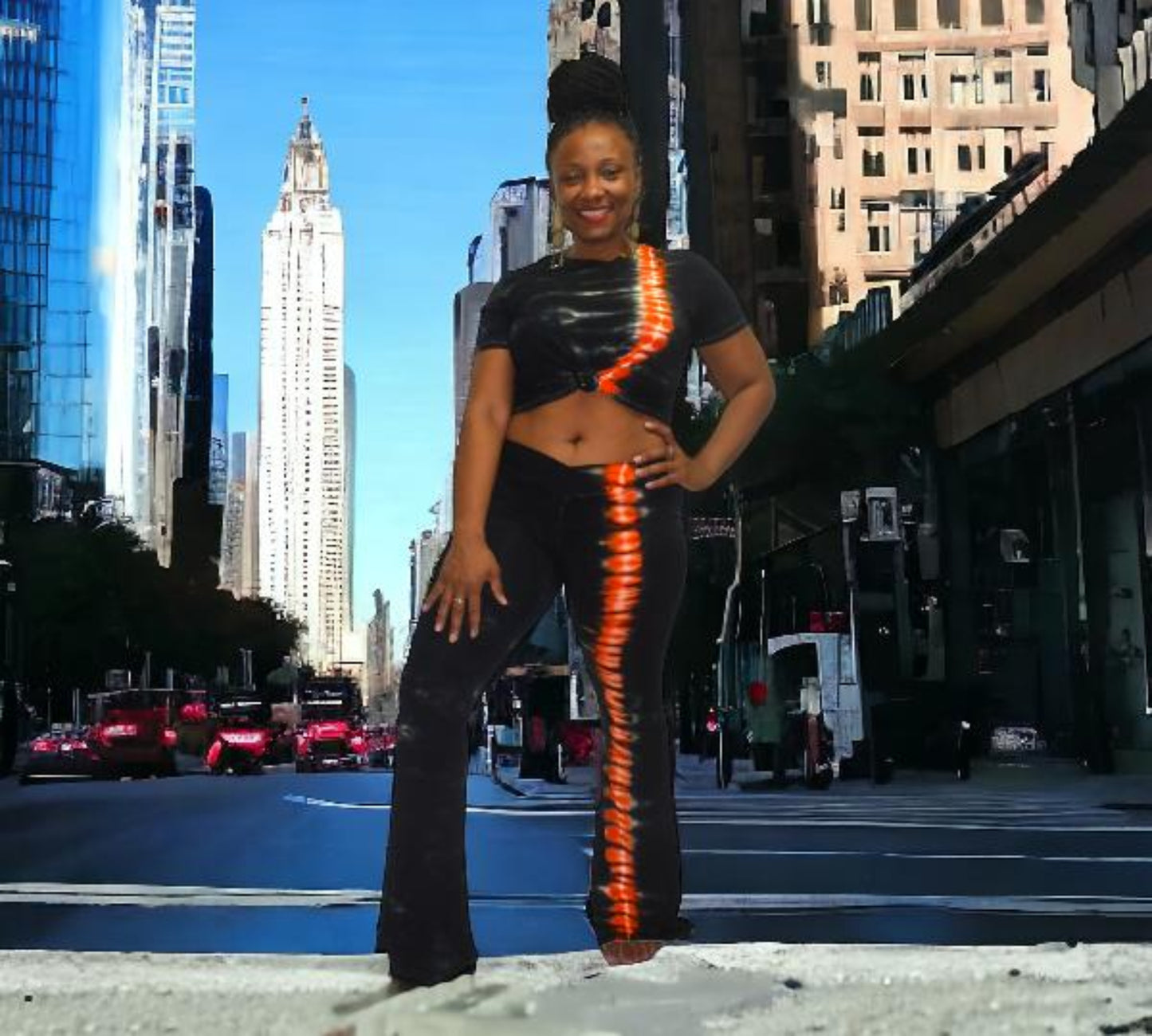Woman posing on a city street wearing a two piece pants set with tall buildings in the background