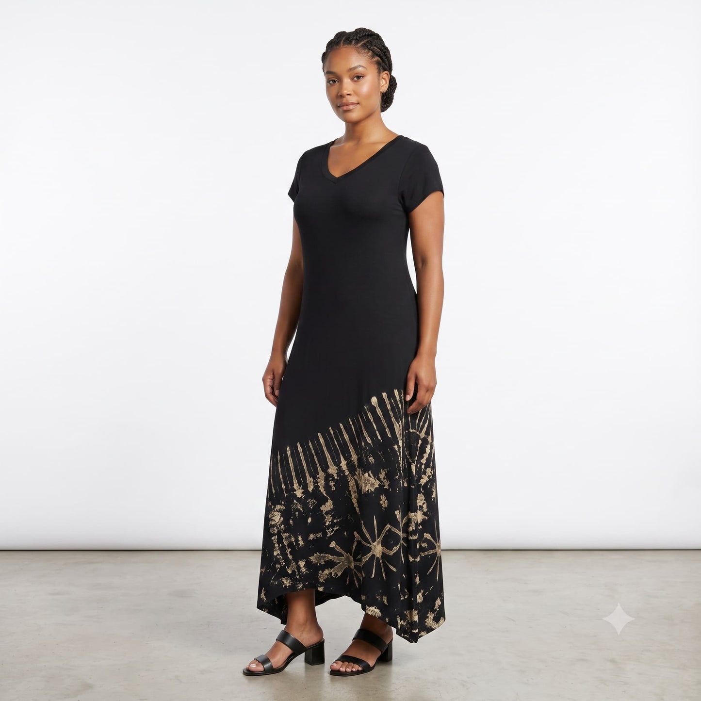 A woman modeling a black short-sleeve maxi dress with a gold abstract pattern on the lower skirt.