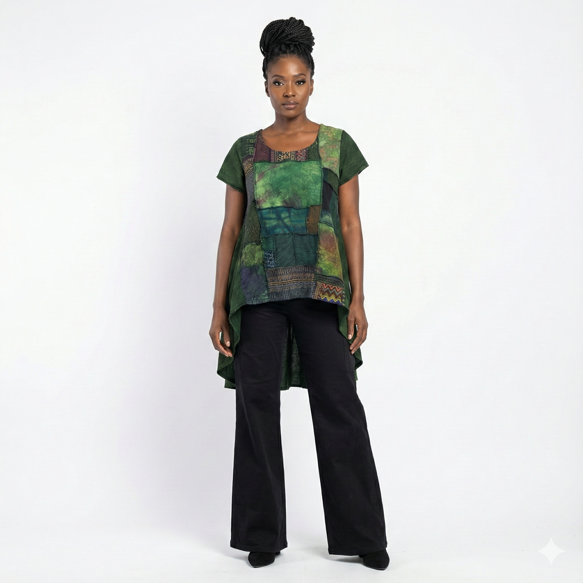 Woman wearing a green and black patterned top with black pants on a white background