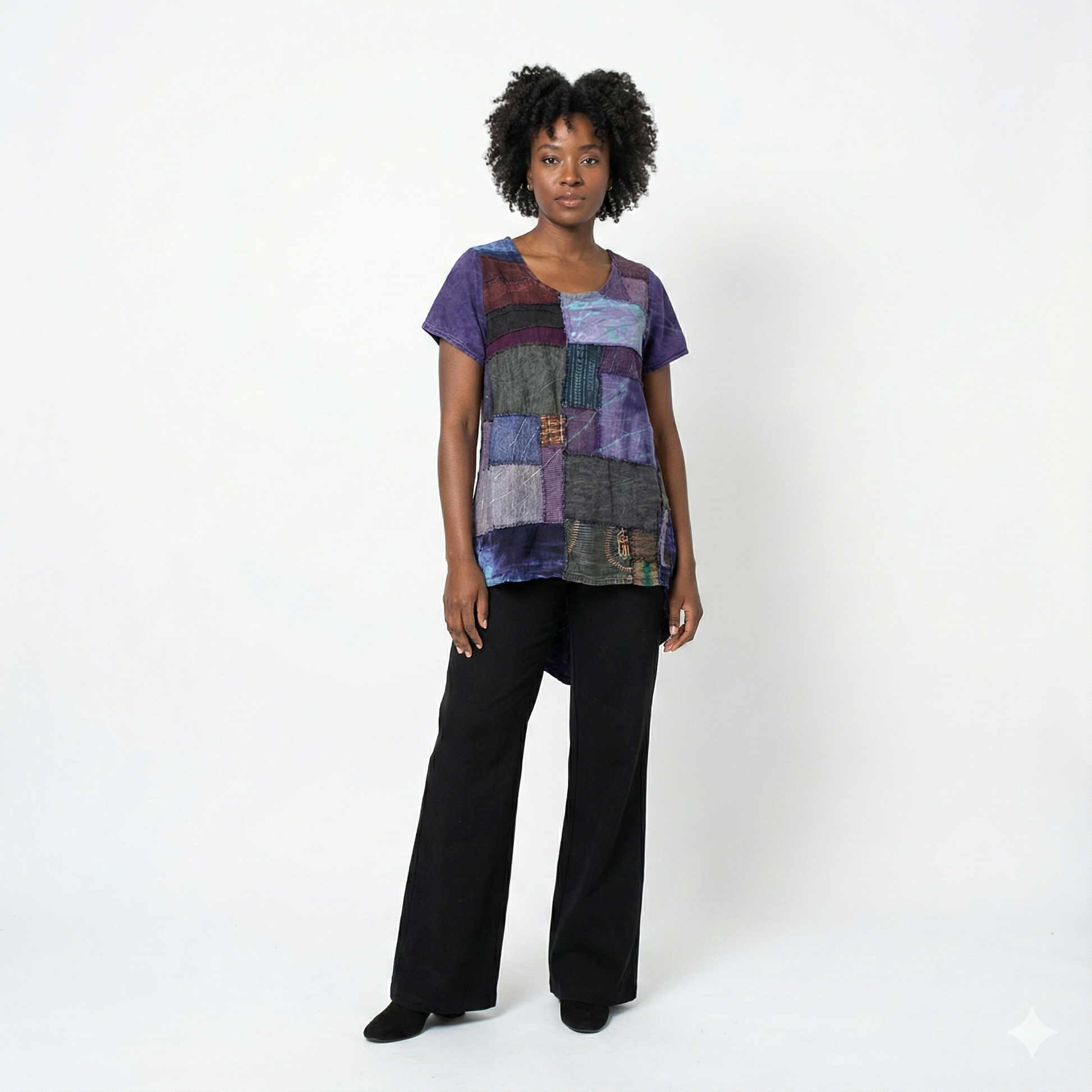 Woman wearing a colorful patchwork top and black pants on a white background