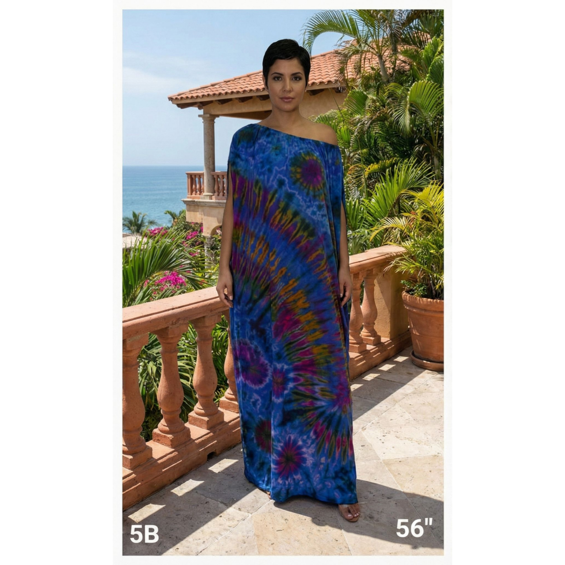 Woman wearing a blue tie-dye dress standing on a balcony with ocean view