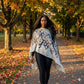 Woman walking in a park with autumn leaves and trees, wearing a silk shawl