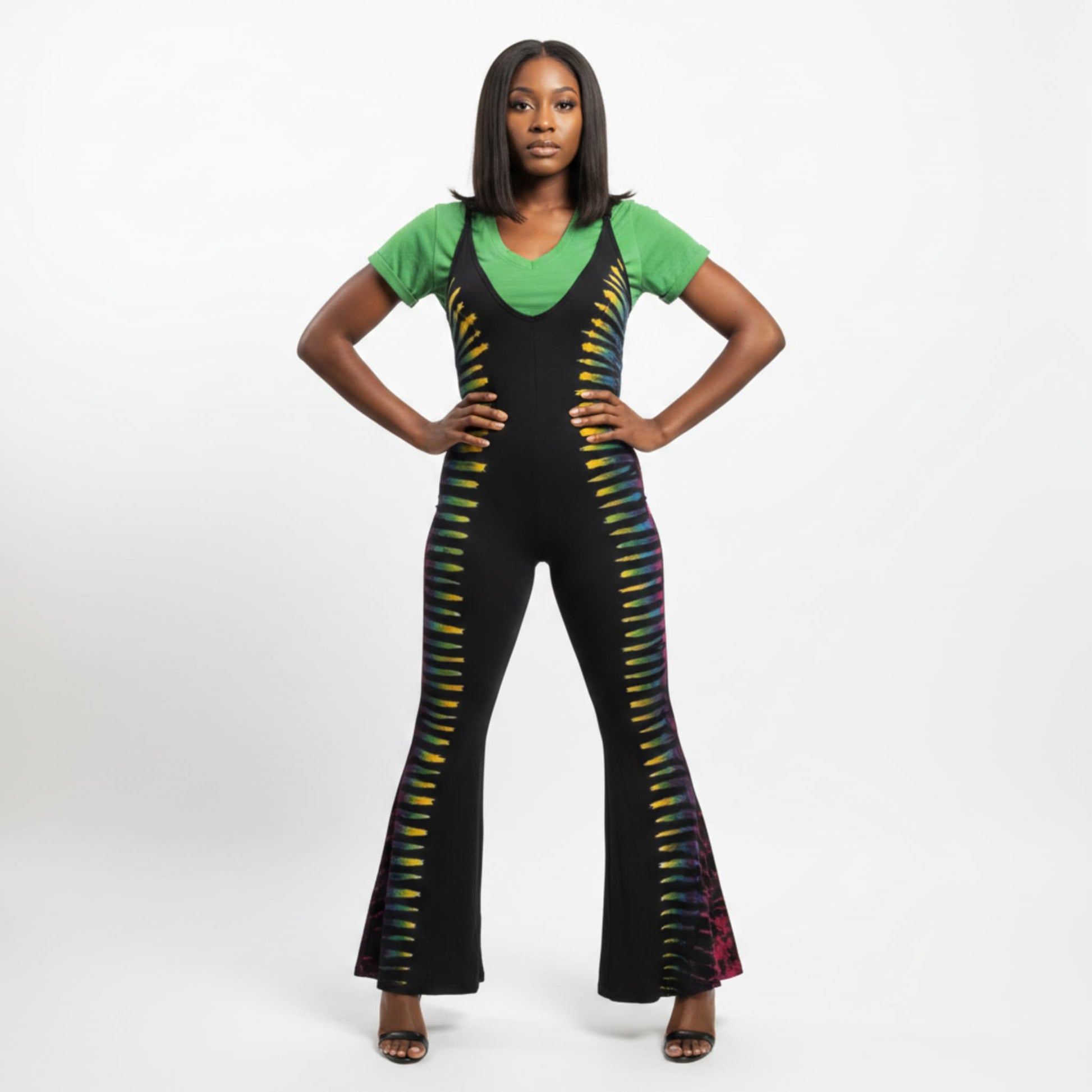 A woman modeling a black flared jumpsuit with vertical multicolor striped accents down the sides