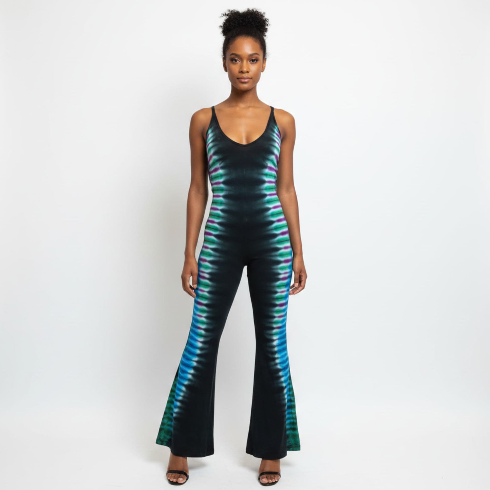 A woman modeling a sleeveless black jumpsuit with a vibrant teal and green tie-dye pattern