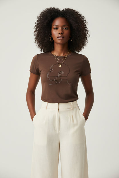 Brown fitted women's t-shirt with a rhinestone bald head design, worn by a model.