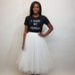 Woman wearing a black t-shirt with text and a white tulle skirt on a plain background