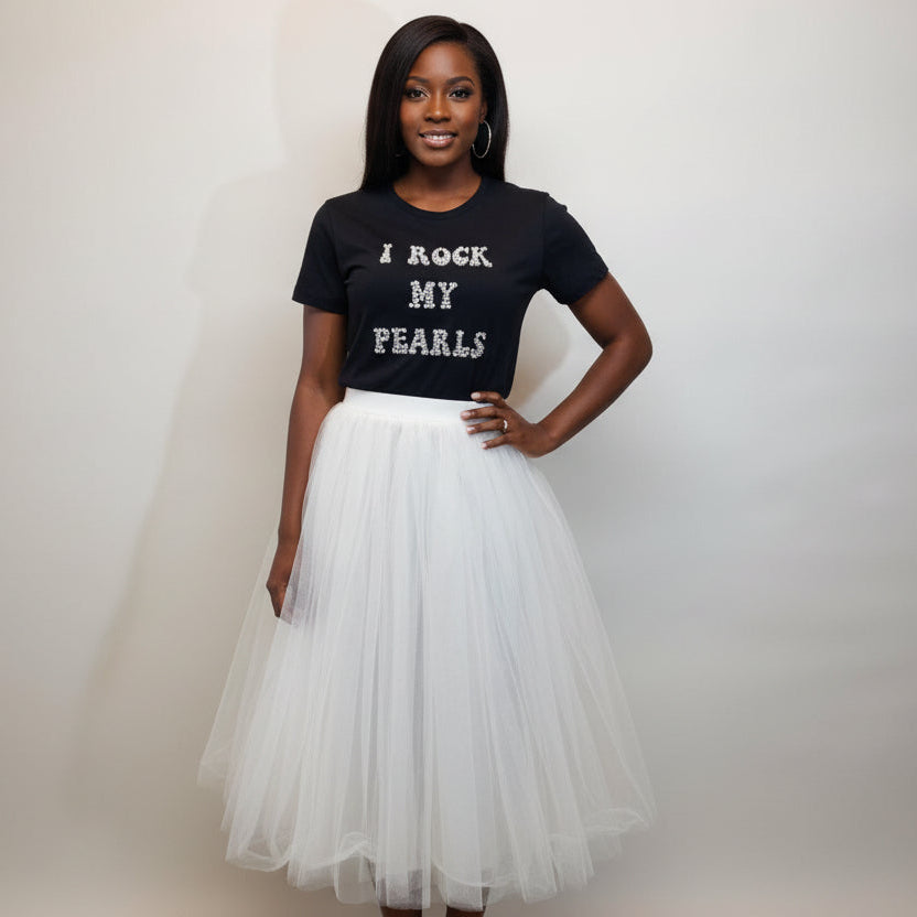 Woman wearing a black t-shirt with text and a white tulle skirt on a plain background