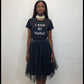 Person wearing a black t-shirt with text and a black tulle skirt on a white background