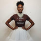 Woman wearing a brown shirt with 'I Rock My Pearls' text and a white skirt against a plain background