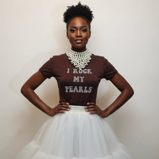 Woman wearing a brown shirt with 'I Rock My Pearls' text and a white skirt against a plain background